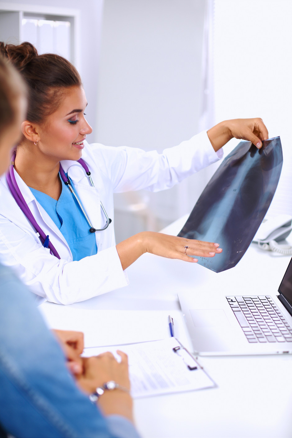 Young female doctor studying x-ray image, sitting