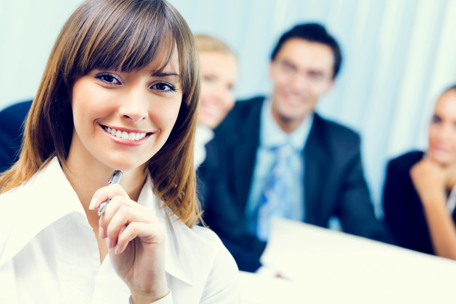 Smiling businesswoman and colleagues on background, at office