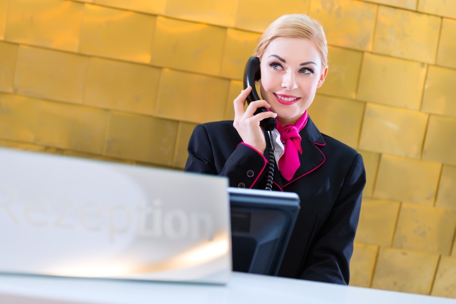 Hotel receptionist with phone on front desk